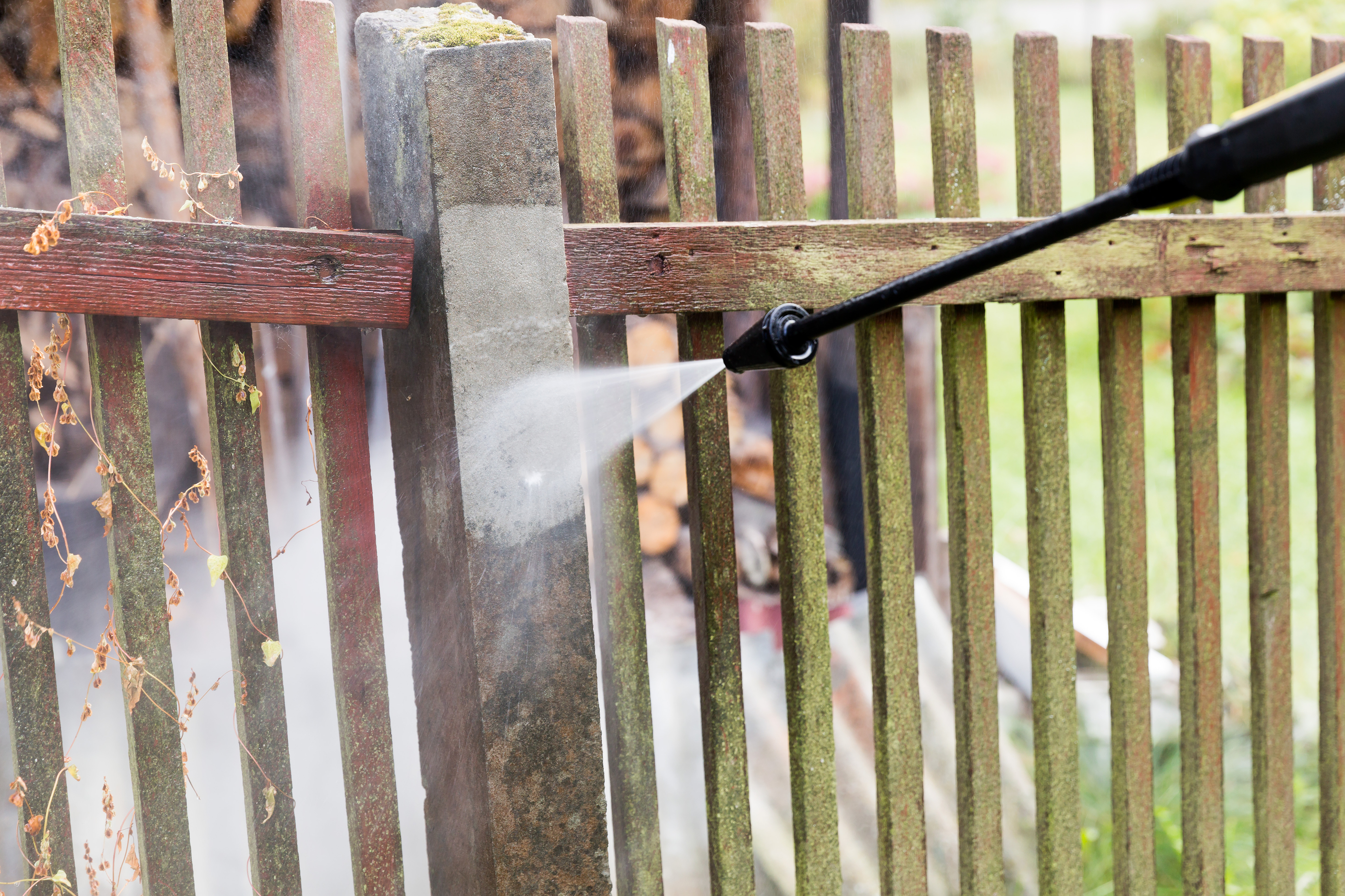 Wooden fence being pressure washed to remove dirt and mildew in OKC
