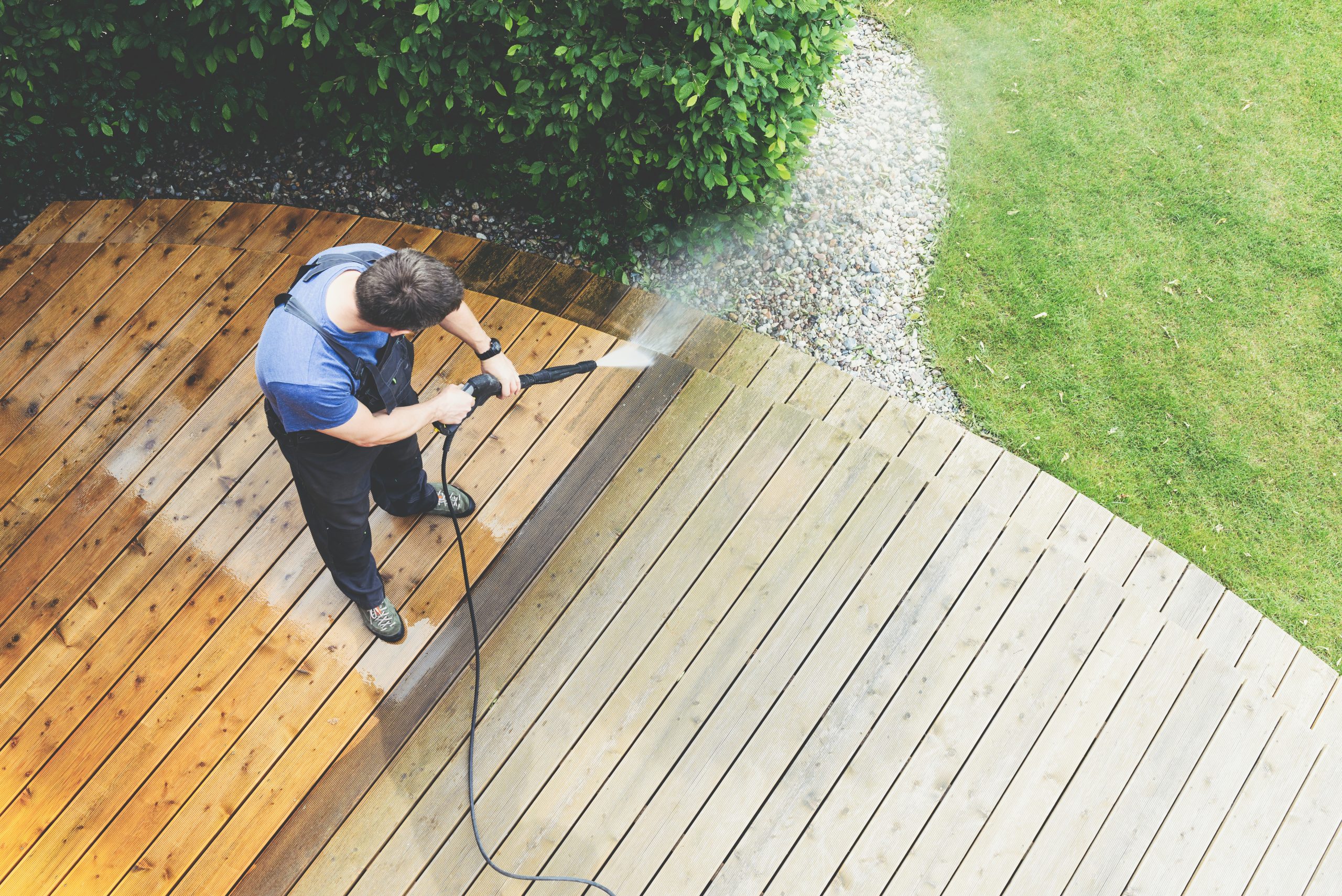 Pressure washing a wooden deck to remove algae and dirt in Oklahoma City